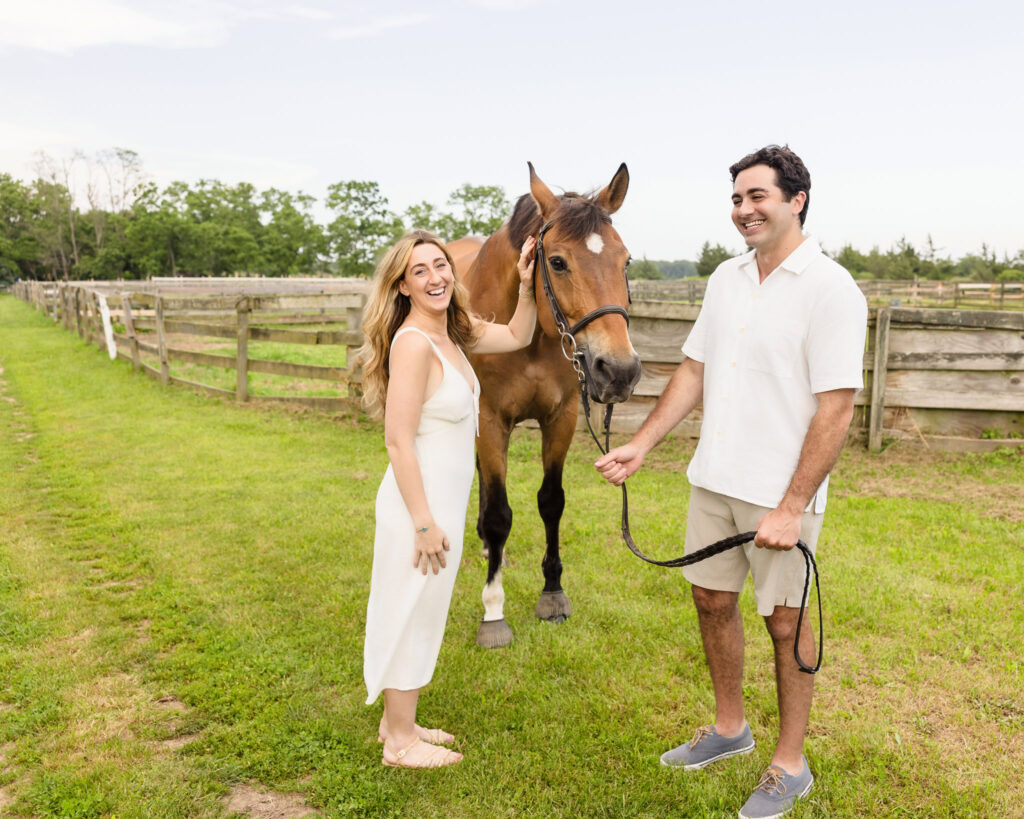 Kristen and James lead a chestnut horse together through the field at Hedgewood Farm.