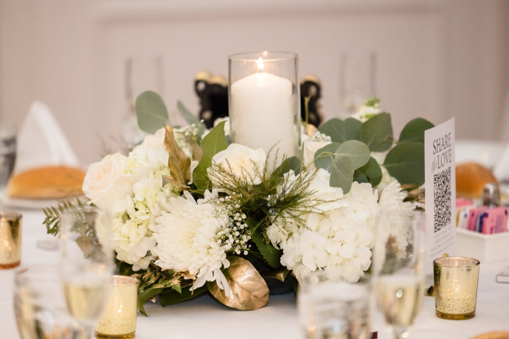 Elegant centerpiece with ivory blooms, candlelight, and gold accents at Stewart Manor Country Club reception.