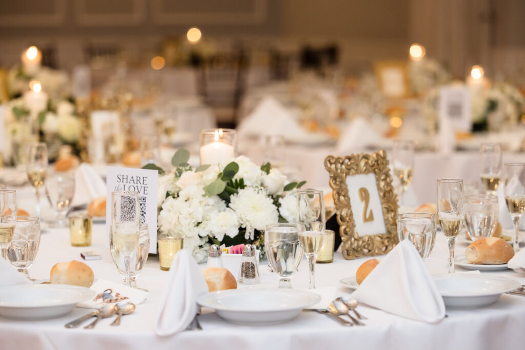 Reception tablescape featuring white florals, gold frames, and romantic lighting at Stewart Manor.
