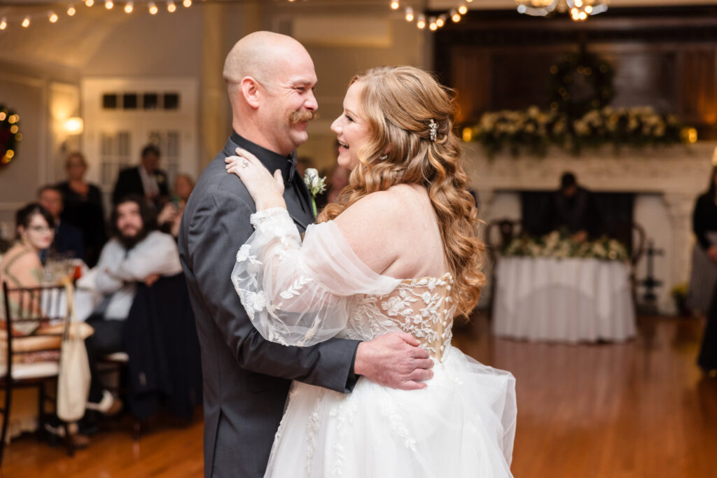 Bride and groom sharing their first dance as guests look on, surrounded by warm lighting and love.