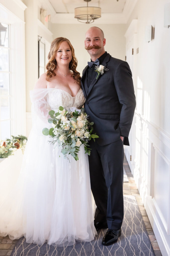 Bride and groom stand together in natural light, framed by soft white architecture at Stewart Manor Country Club.