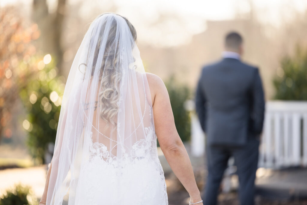 Bride approaches her groom from behind during their emotional first look moment on the outdoor terrace at Stonebridge Country Club.