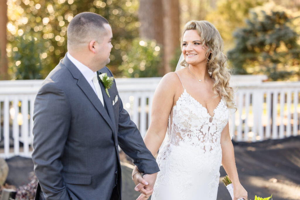 Bride and groom hold hands and share a joyful smile just after their first look, standing together on the grounds of Stonebridge Country Club.

