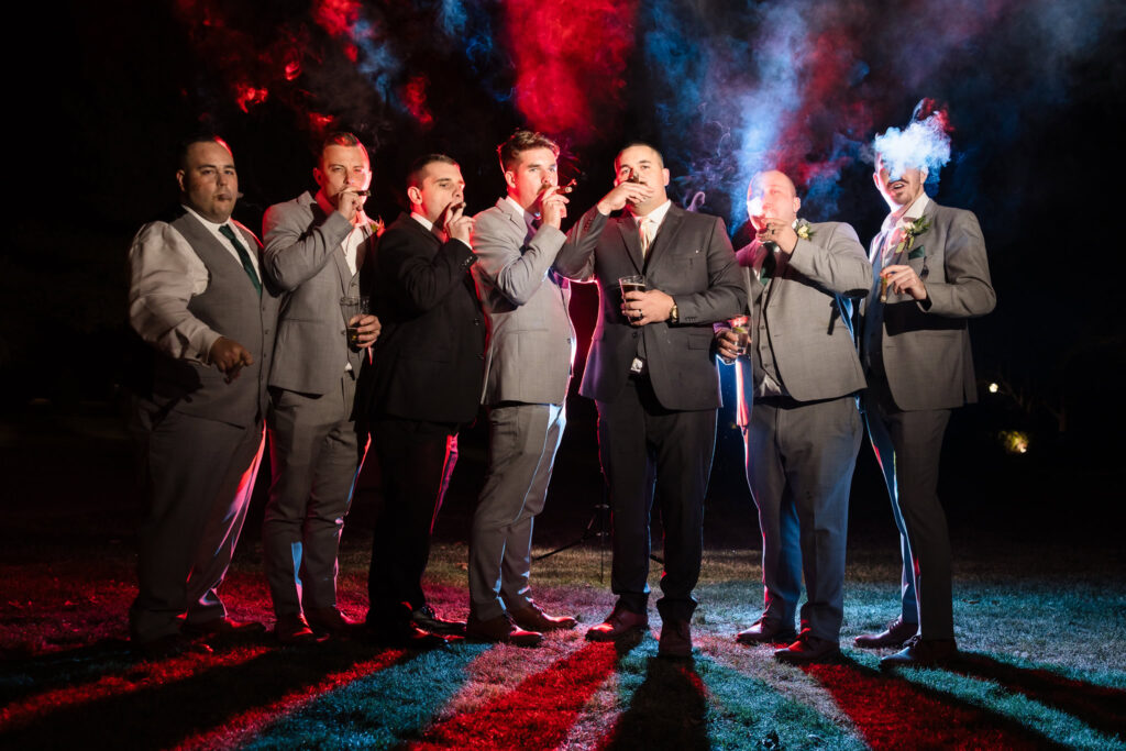 Groom and groomsmen pose confidently in dramatic lighting and colored smoke at Stonebridge Country Club, adding a bold and modern twist to classic portraiture.

