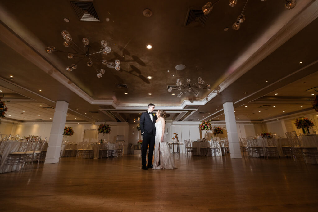 Bride and groom sharing a quiet moment together in the grand reception ballroom at Watermill Caterers before the celebration begins.