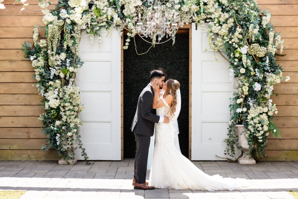 Just married couple kissing under floral arch