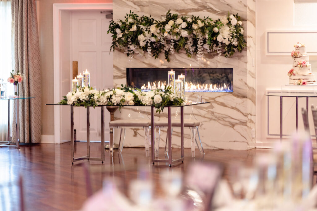 Reception sweetheart table with florals and fireplace backdrop
