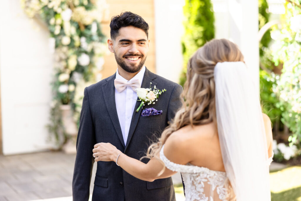 Bride and groom smiling at each other in quiet courtyard moment