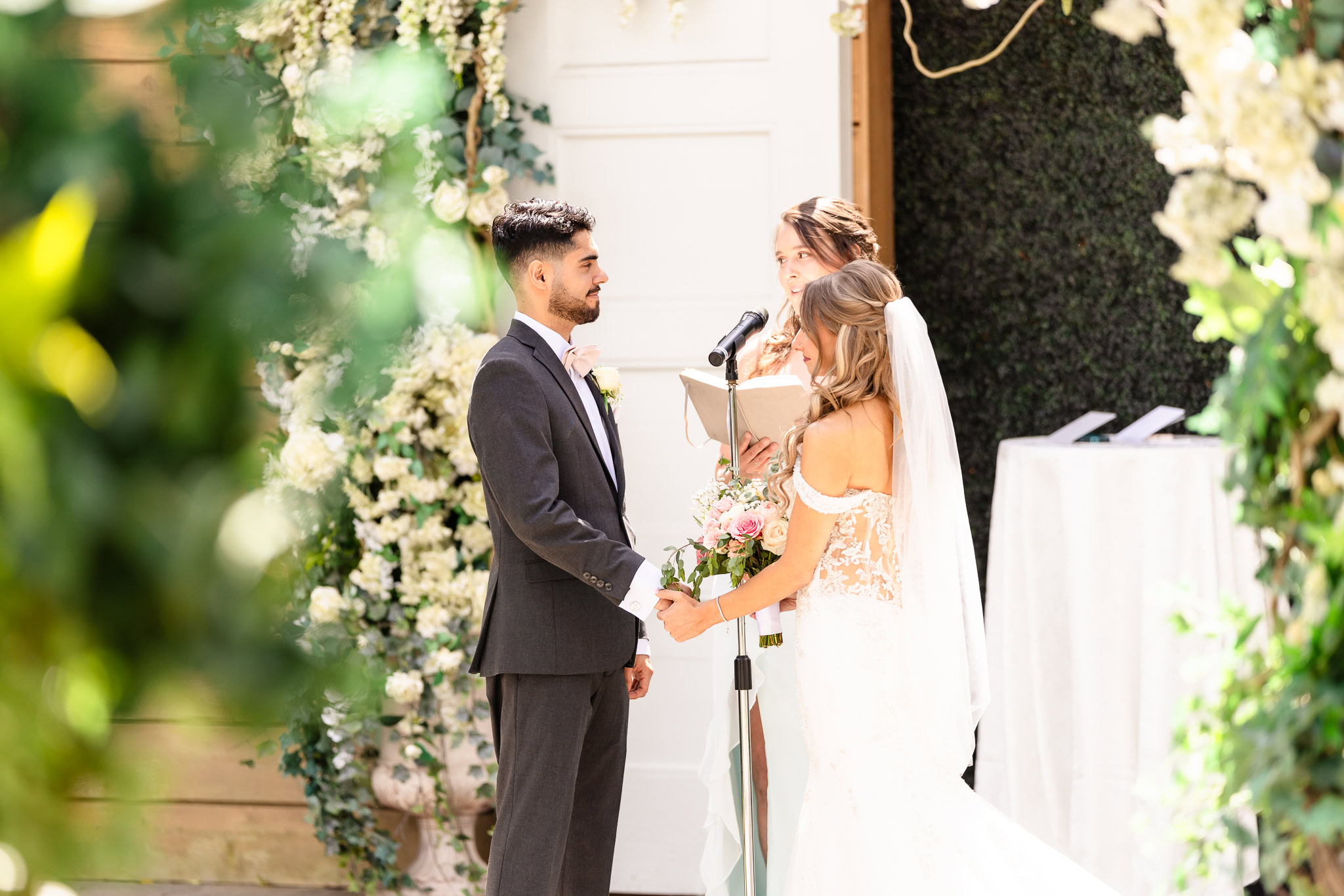 Bride and groom exchanging vows during a sunlit outdoor ceremony at the Watermill.