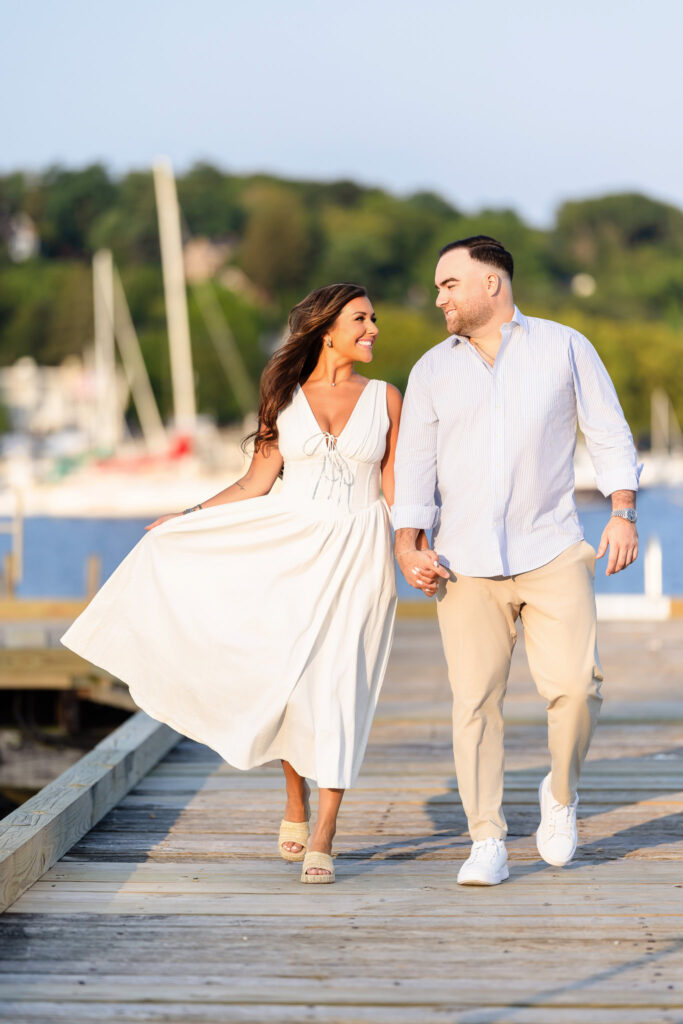 Couple walking hand in hand along the marina walkway, Christine’s dress flowing in the breeze.
