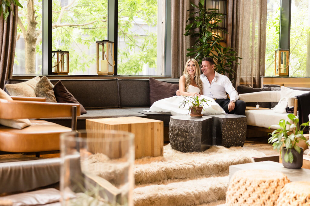 Couple sitting together in the lounge at 1 Hotel Brooklyn Bridge during their summer engagement session.