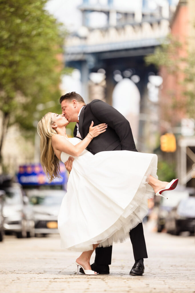 Couple kissing in a dip on the cobblestones of Washington Street with the Manhattan Bridge behind them.