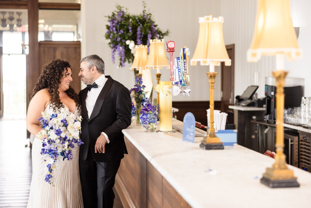 Bride and groom sharing a quiet moment near the bar inside Gatsby on the Ocean, with elegant lamps and décor in view.