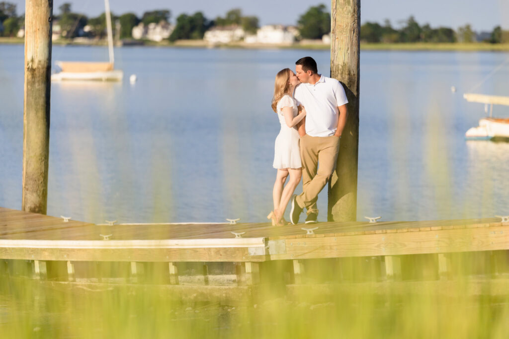 Couple standing close by the water’s edge, sailboats in the distance at Greenwich Point Park.