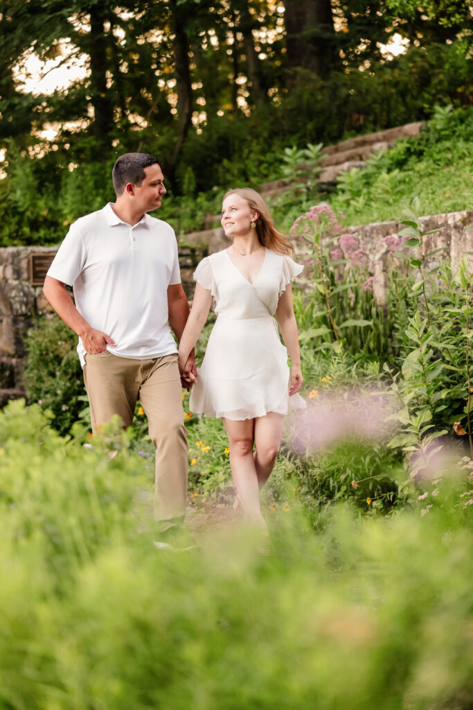 Couple walking together through sunlit greenery at Greenwich Point Park.