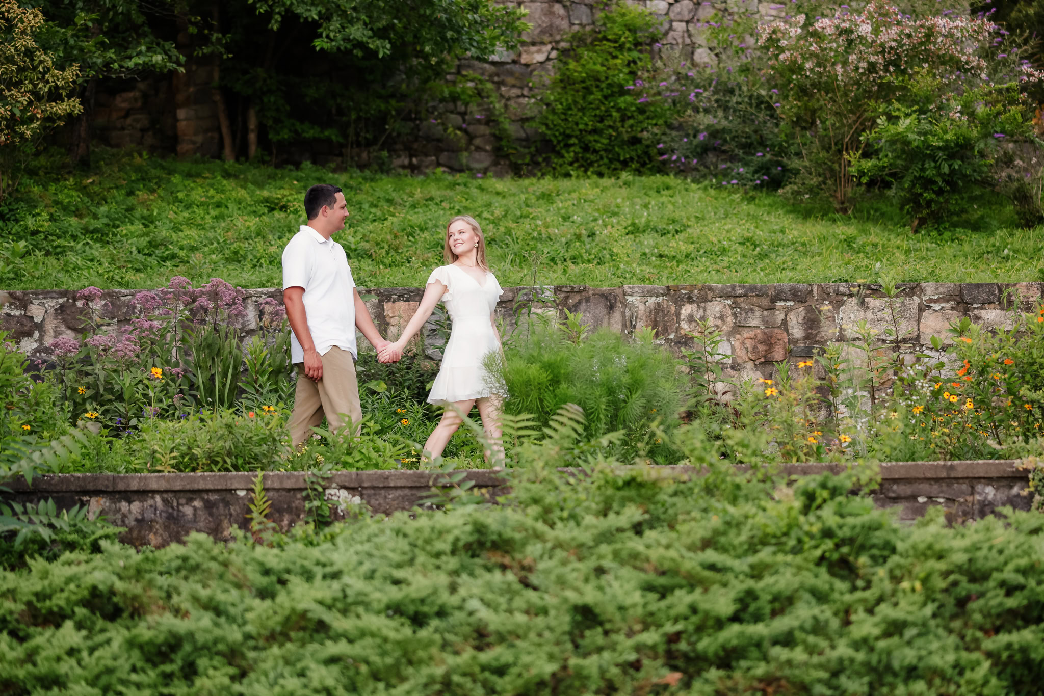 Couple joyfully walking through lush greenery, holding hands at Greenwich Point Park.