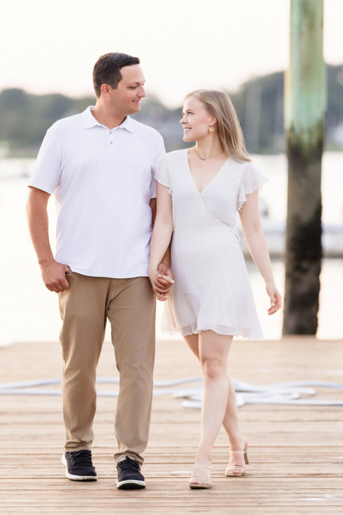 Couple walking along a wooden dock, laughing together at Greenwich Point Park.