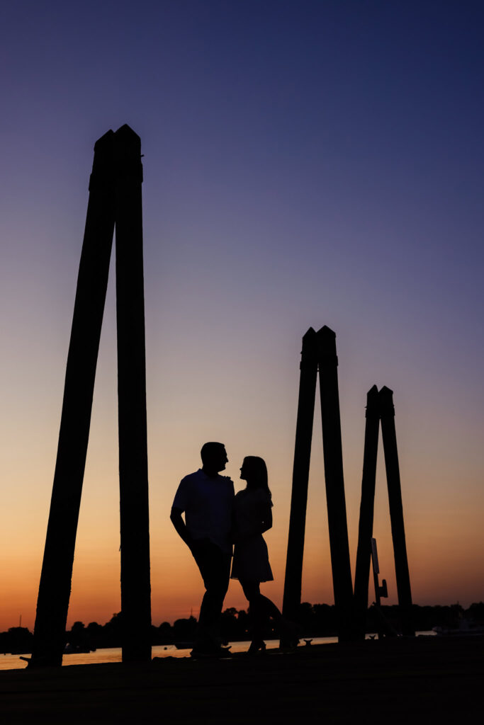 Silhouette of couple standing beneath tall pier structures at dusk at Greenwich Point Park.