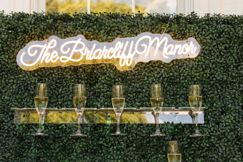 Champagne wall with personalized wedding signage during cocktail hour at Watermill Caterers.