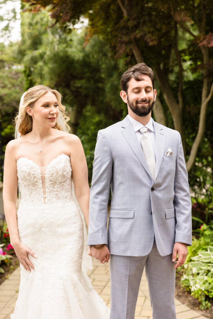 Bride and groom standing hand in hand outside the mansion gardens, smiling softly in anticipation of their ceremony.