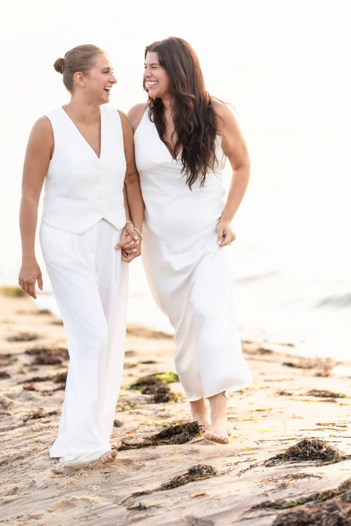 Couple strolling along the beach at Robert Moses State Park, smiling at each other as the evening sky softens in pastel hues.