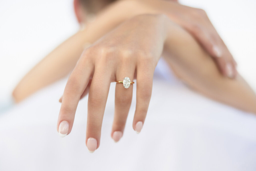 Close-up of a gold oval engagement ring on hand during a proposal at Sands Point Preserve.