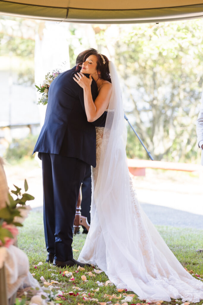 Bride Sabrina hugging her father during the wedding ceremony at Camp Pa-Qua-Tuck, surrounded by petals and emotion.