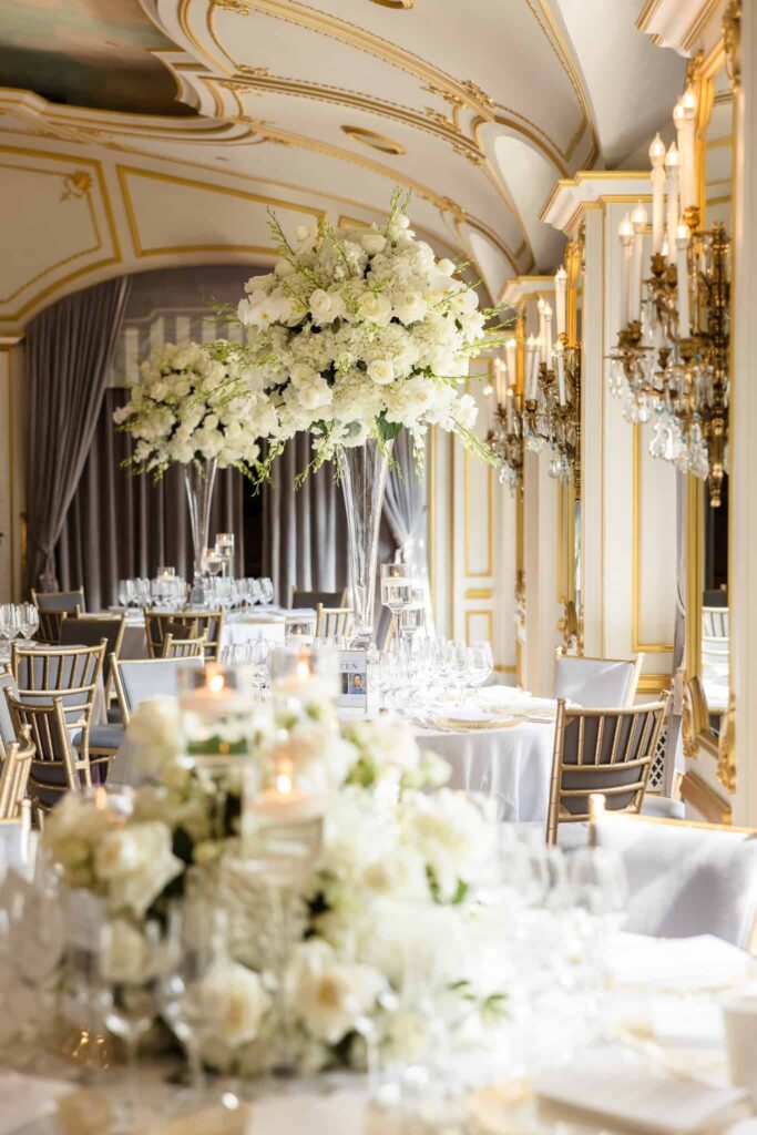 St. Regis New York wedding reception with tall white floral centerpieces in crystal vases, gold chairs, and candlelit tables.
