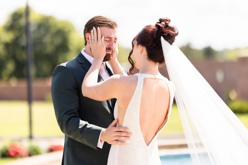 Emotional first look between bride and groom at Hiland Park Country Club, as the bride gently holds his face and he wipes away tears of joy.