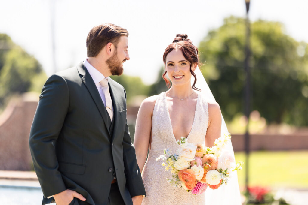 Bride and groom sharing a joyful moment after their first look at Hiland Park Country Club, with the bride holding a romantic bouquet of peach, cream, and blush florals.