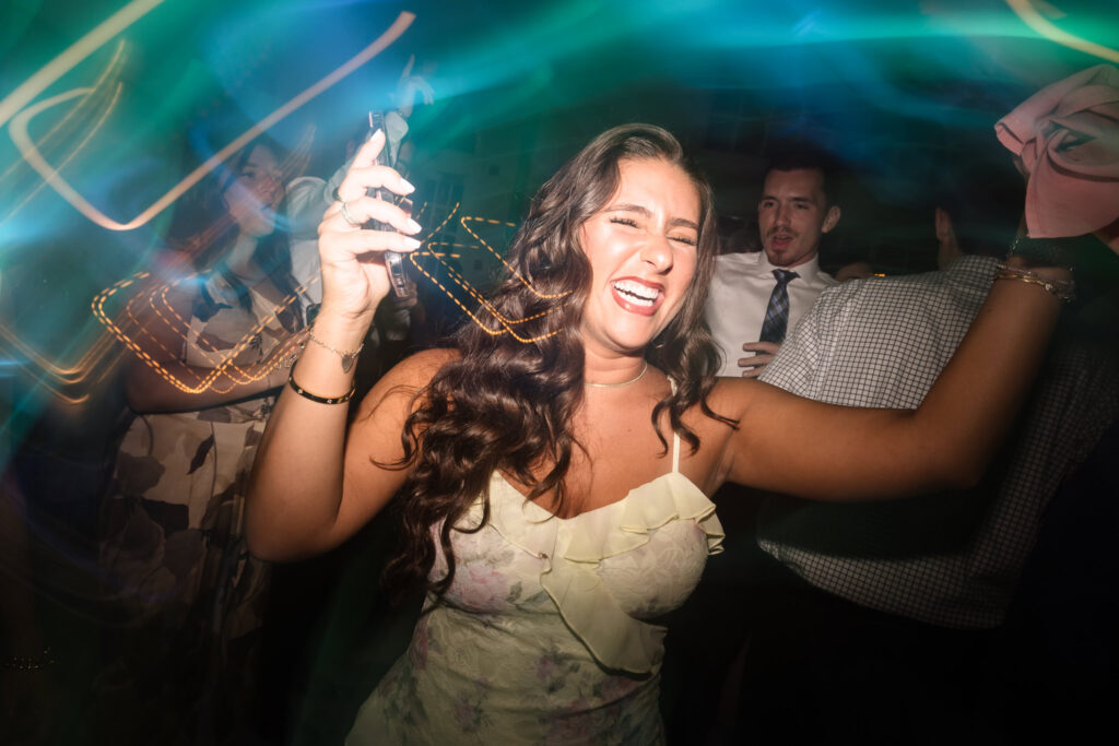 Guest dances with pure joy and energy under vibrant reception lights at Hiland Park Country Club, captured during a lively wedding celebration.