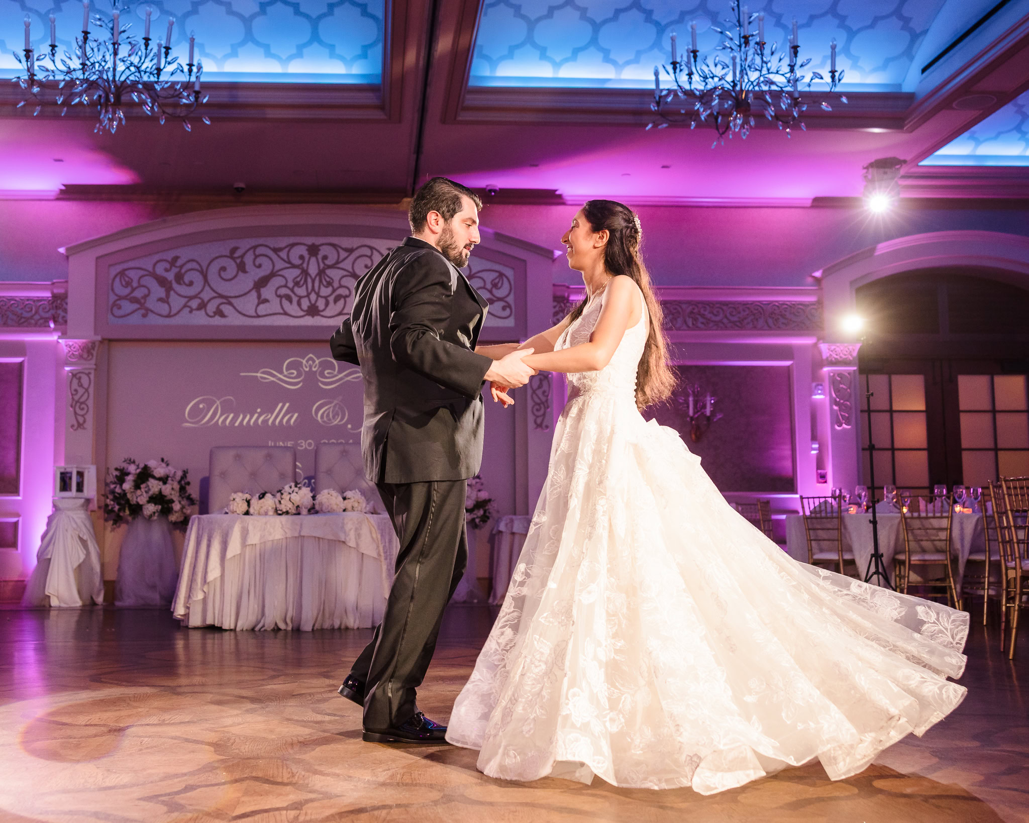 Bride and groom share their first dance under romantic purple lighting in the elegant ballroom at Larkfield Manor, Long Island wedding venue.