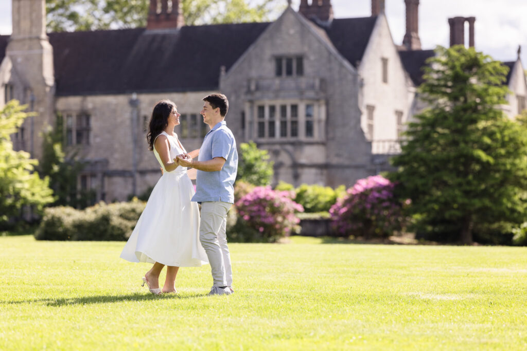 Romantic engagement photo of a couple dancing on the great lawn at Planting Fields Arboretum with the historic Coe Hall mansion in the background.