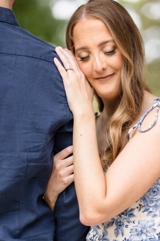 Bride-to-be resting her head on her fiancé’s shoulder, showcasing her engagement ring during their fall session.