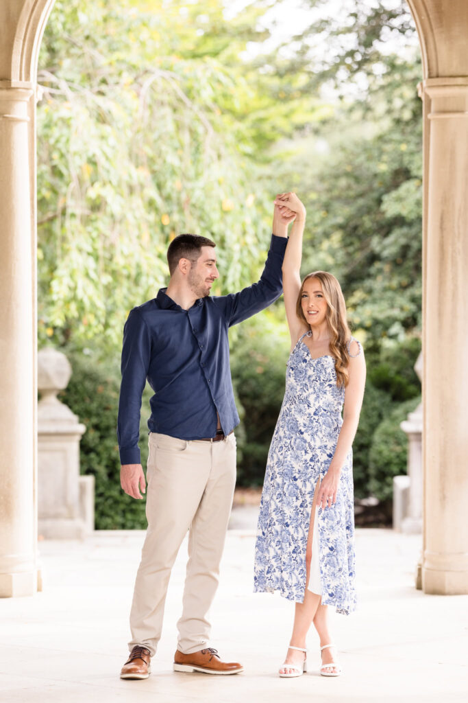 Couple shares a joyful dance beneath the elegant stone archways of Coe Hall during their fall engagement session.