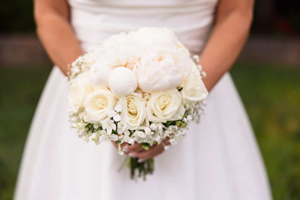 Close-up of bride holding an elegant white rose and peony bouquet before her waterfront wedding at The Snapper Inn in Oakdale, Long Island.