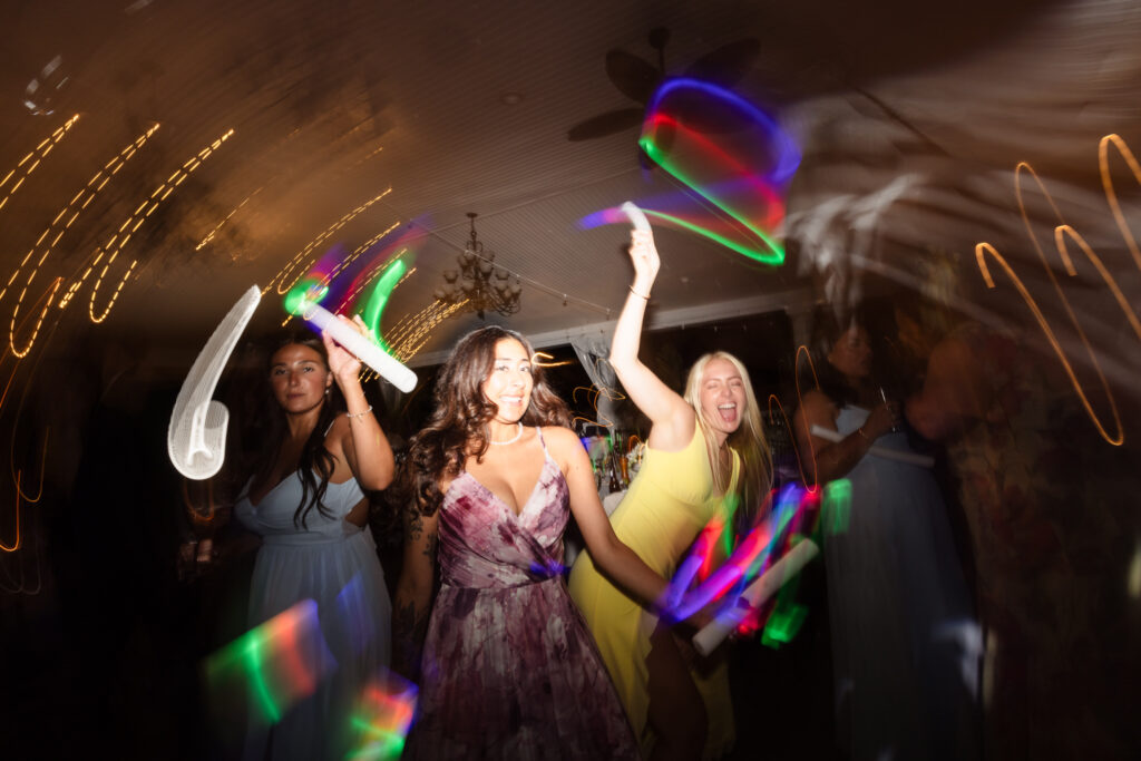 Wedding guests dancing with colorful light sticks during a fun nighttime reception at The Snapper Inn in Oakdale, Long Island.