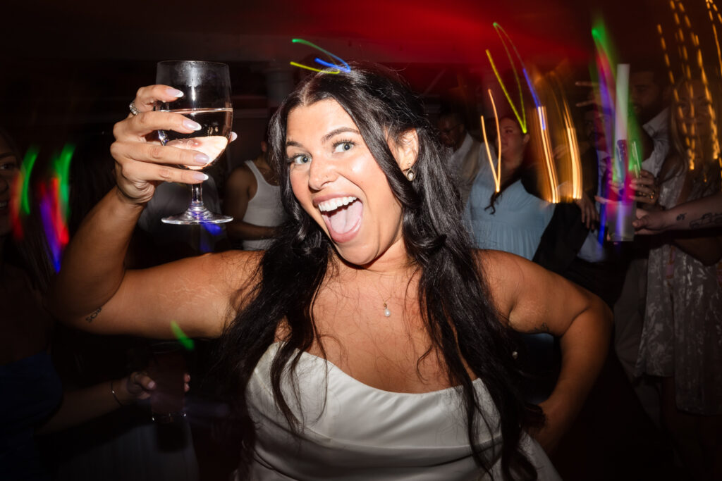 Bride raising a glass in celebration during the lively dance floor party at The Snapper Inn wedding reception in Oakdale, Long Island.