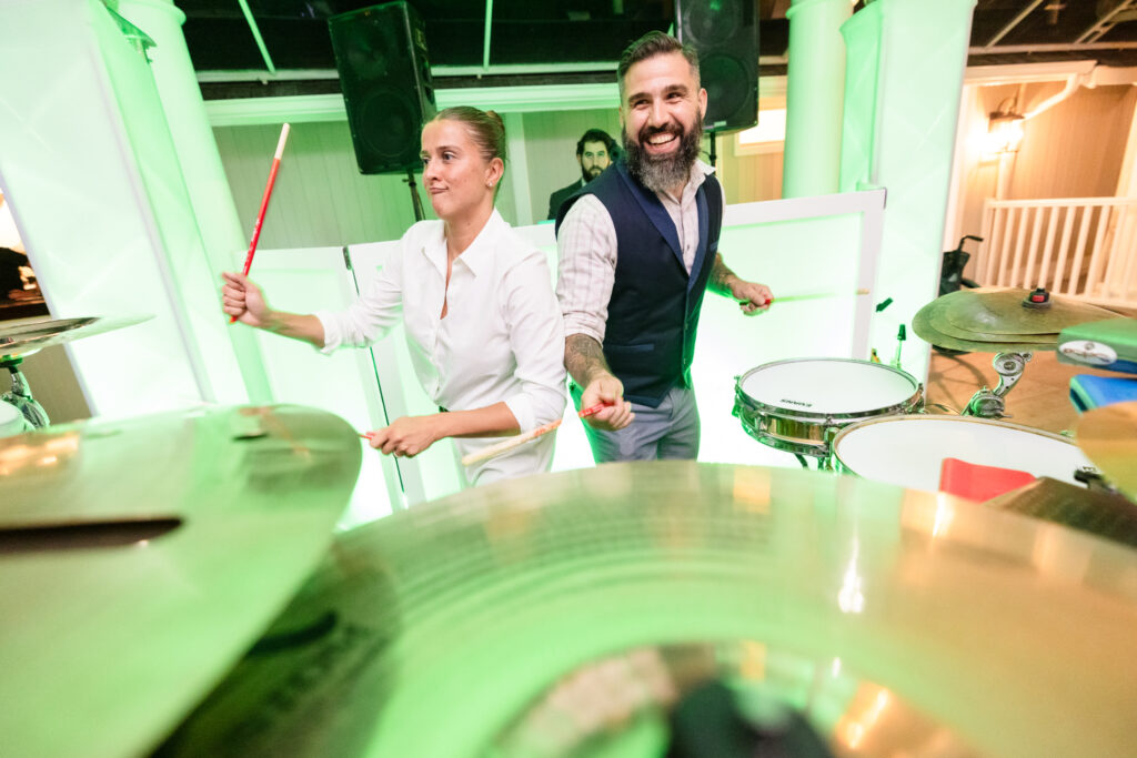 Bride and guest drumming together during the high-energy wedding reception at The Snapper Inn in Oakdale, Long Island.