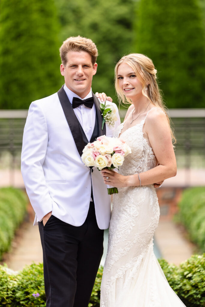 Bride and groom smiling together in Larkfield Manor’s garden after their first look, showcasing elegant summer wedding style and romantic florals.