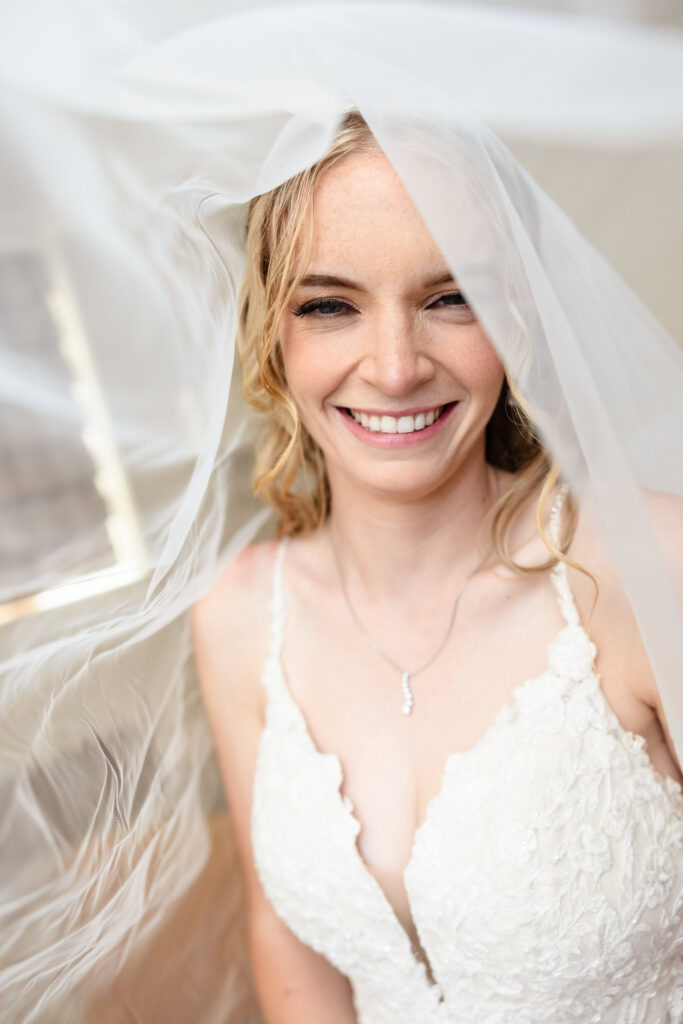 Bride smiling softly under her flowing veil, showcasing her lace wedding dress and natural bridal beauty at Larkfield Manor.