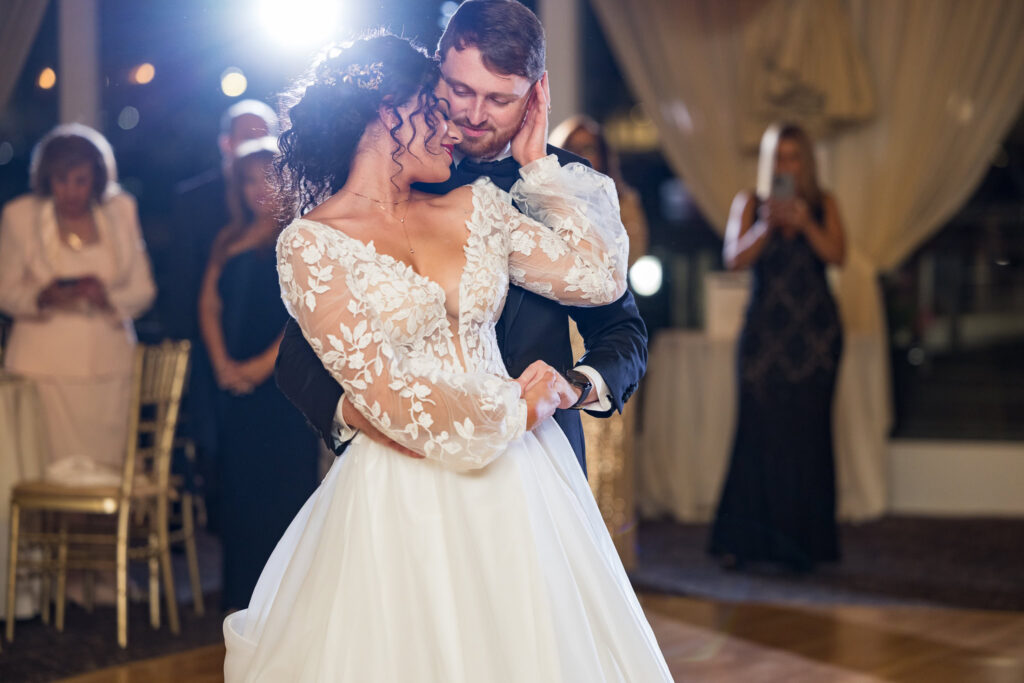 Bride and groom share a tender cinematic moment during their first dance, softly illuminated by backlight, captured with cinematic wedding photography to highlight their emotional connection and romantic embrace.