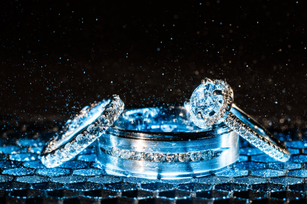 Close-up of diamond engagement ring, wedding band, and eternity ring sparkling against a dark, glittering background a luxurious detail that reflects premium craftsmanship.