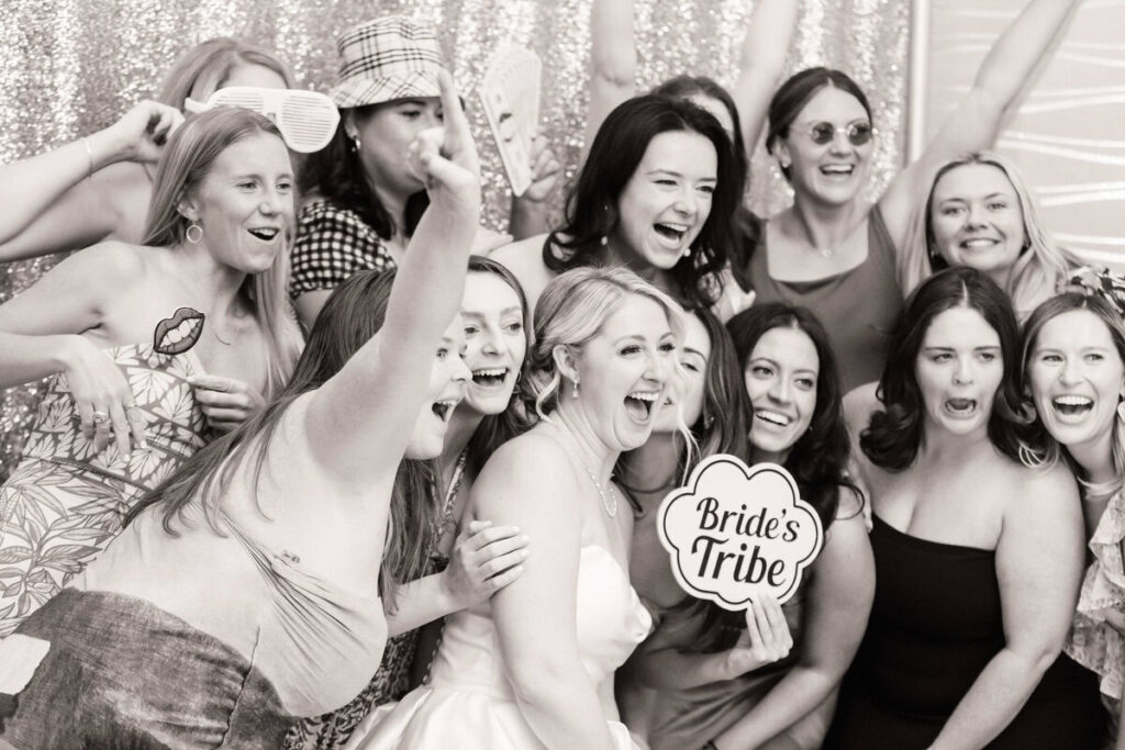 Bride surrounded by her joyful bridal party in a fun, candid group shot, helping everyone look natural in your wedding photos with props and laughter during the wedding reception
