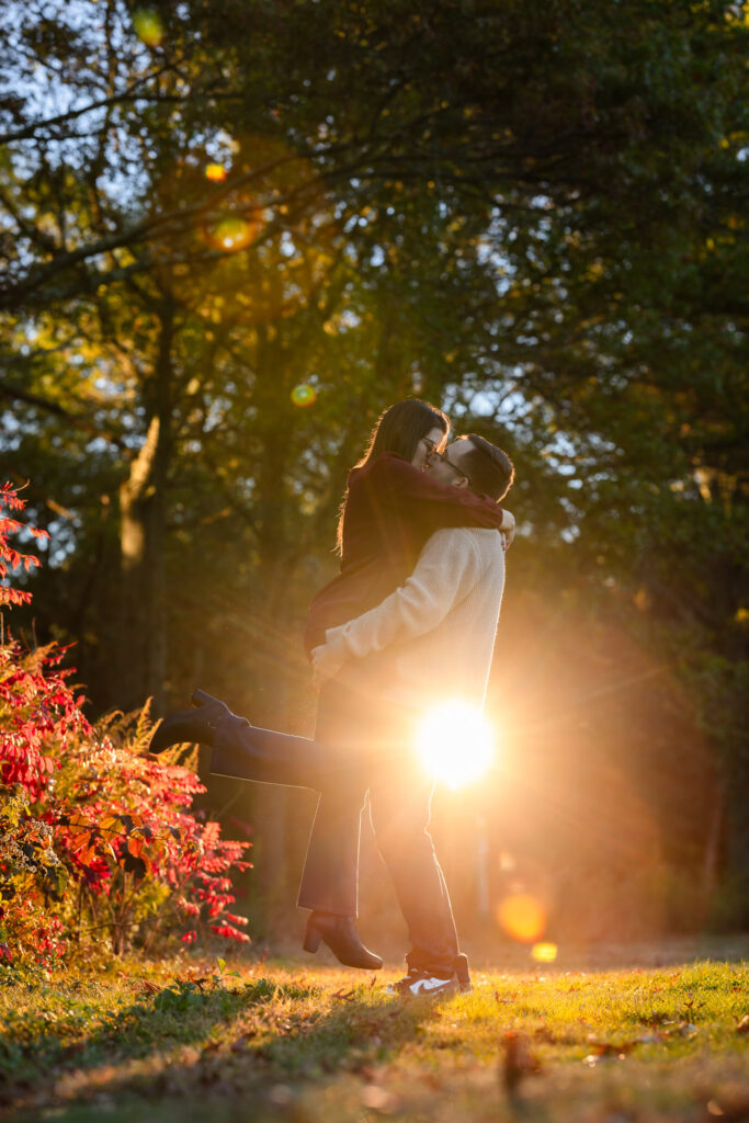 Fiancé lifting his bride-to-be into a kiss as the golden sunset creates a romantic backlight during at Bethpage State Park.