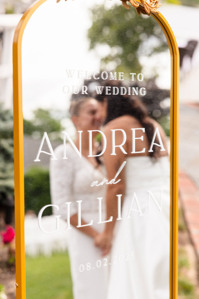 Wedding welcome sign reflecting the brides holding hands and smiling on their waterfront wedding day.