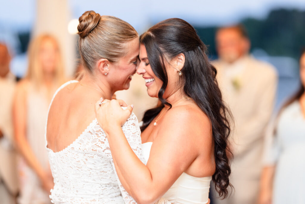 Brides sharing an emotional first dance, holding each other closely and smiling during their Snapper Inn wedding reception.