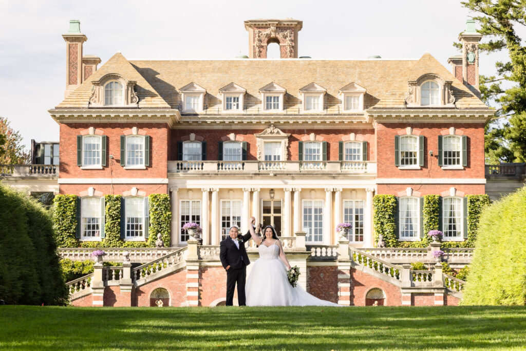 Bride and groom dancing on the lawn in front of the grand red-brick mansion at Old Westbury Gardens, capturing timeless estate wedding elegance.