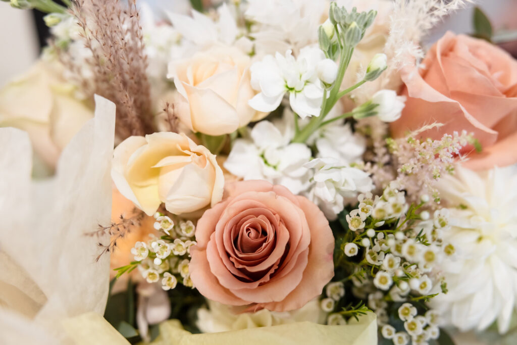 Close-up of a romantic bridal bouquet with blush roses, cream florals, and textured greenery for a fall wedding at Gatsby on the Ocean.