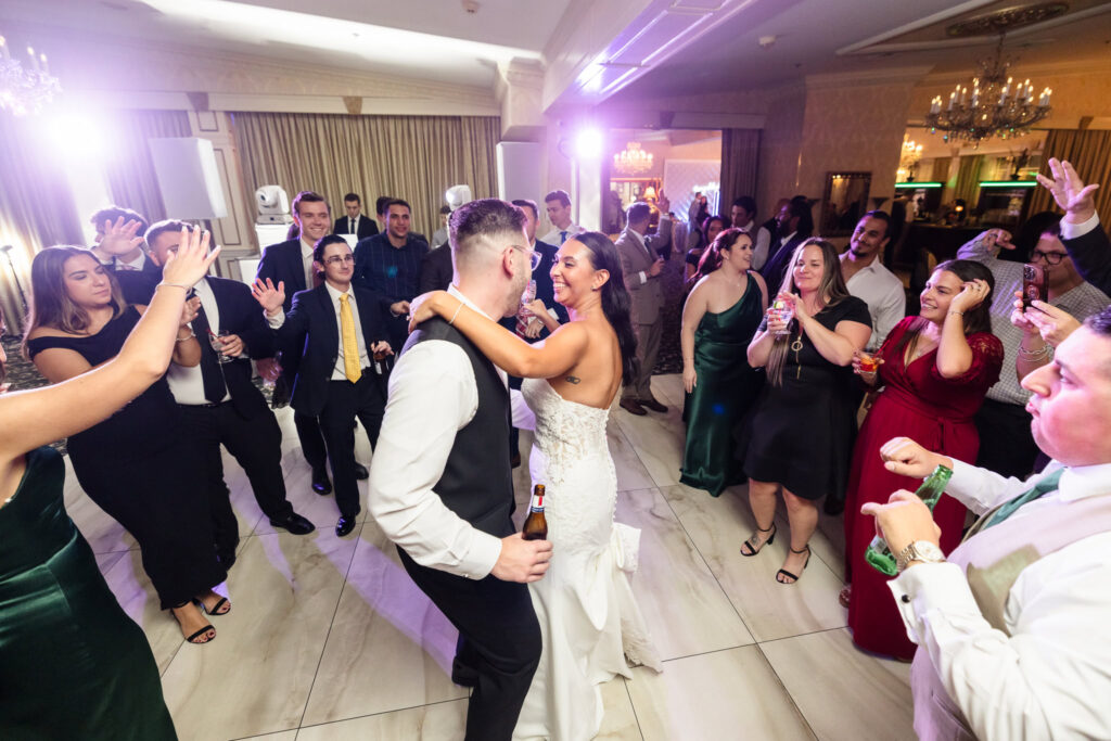 Bride and groom dancing joyfully together surrounded by cheering guests during their wedding reception at Giorgio’s Baiting Hollow.